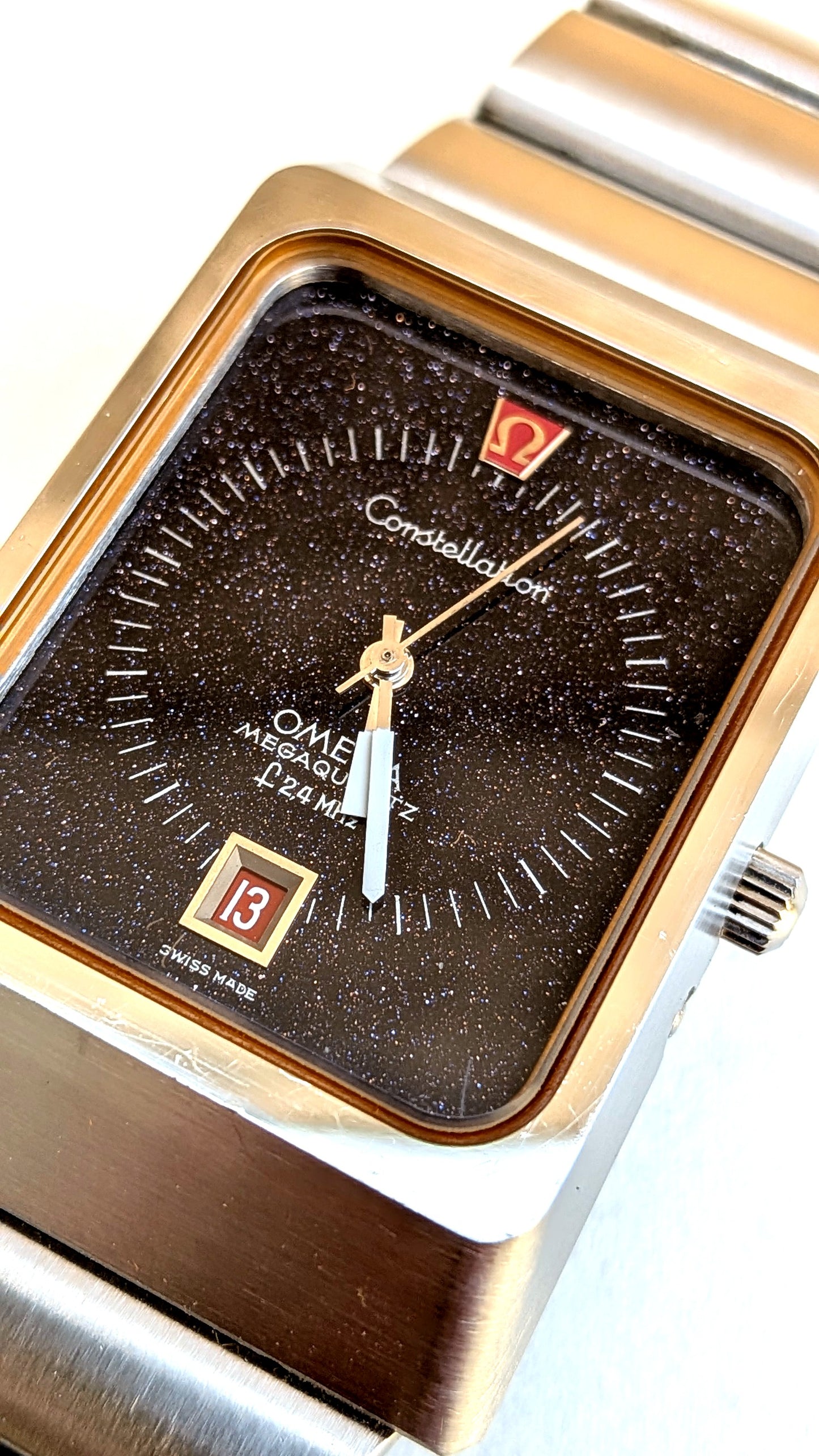 Omega Constellation Megaquartz gros plan cadran aventurine brun, index appliqués et guichet date, montre vintage homme
