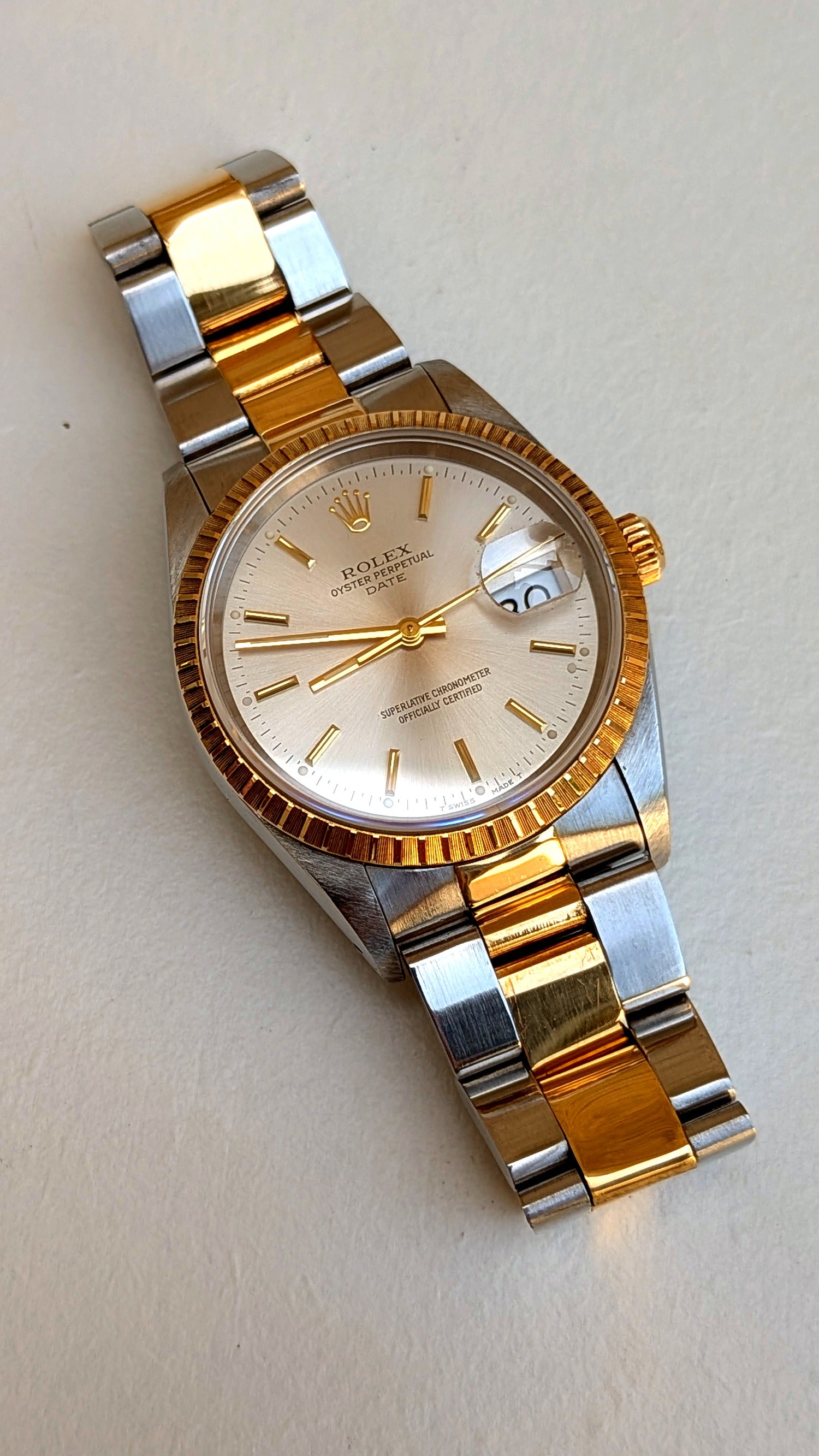 Rolex Oyster Perpetual Date posée en diagonale, cadran argenté et bracelet Oyster acier-or, montre vintage homme
