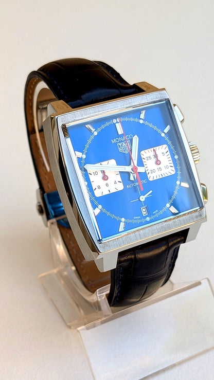 TAG Heuer Monaco chronographe cadran bleu sur support, bracelet cuir noir, vue trois-quarts, montre vintage homme