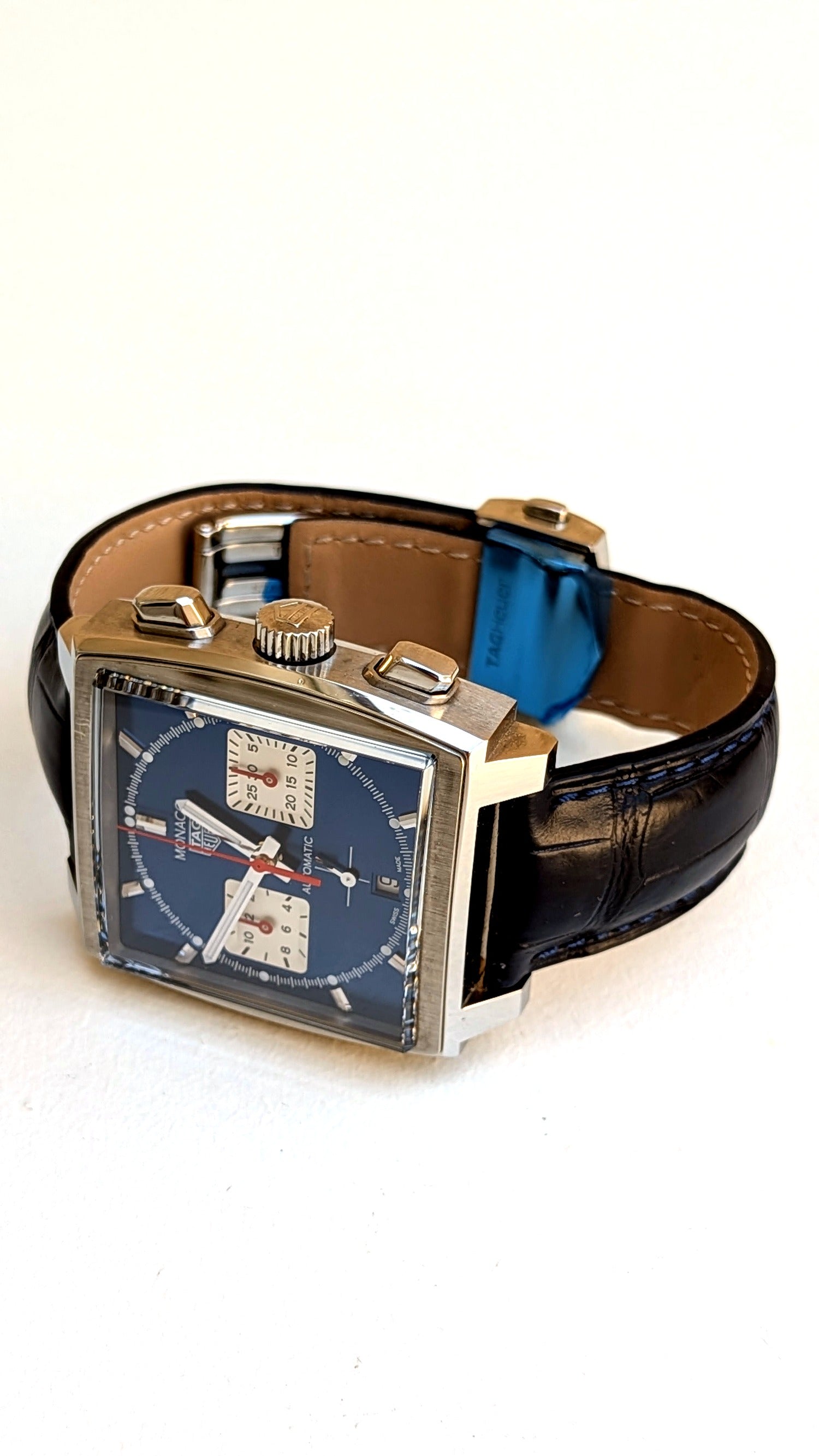 TAG Heuer Monaco vue latérale, couronne et poussoirs, bracelet cuir noir surpiqûres bleues, montre vintage homme