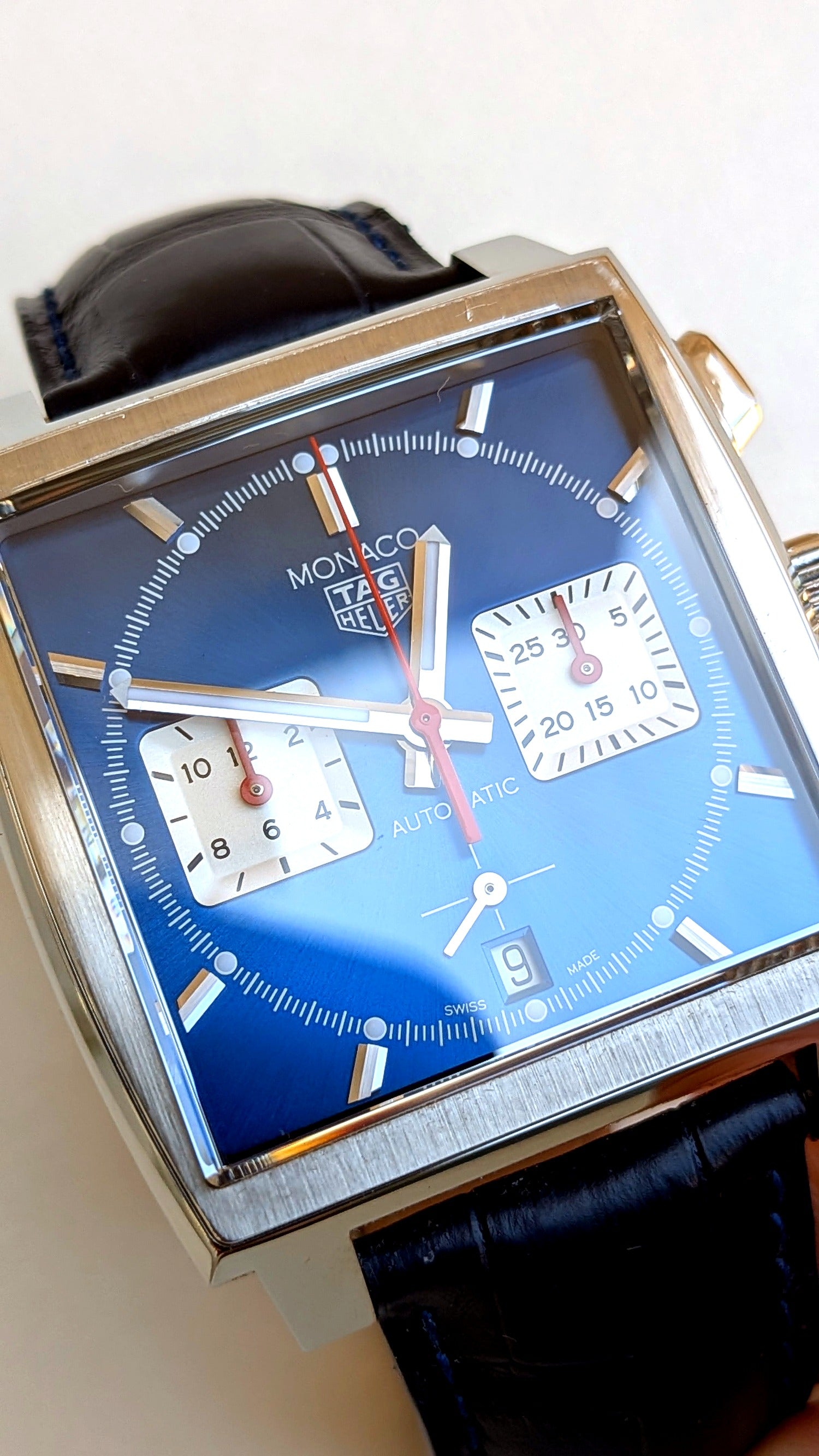 TAG Heuer Monaco cadran bleu en angle, logo Monaco TAG Heuer et compteurs, bracelet cuir, montre vintage homme