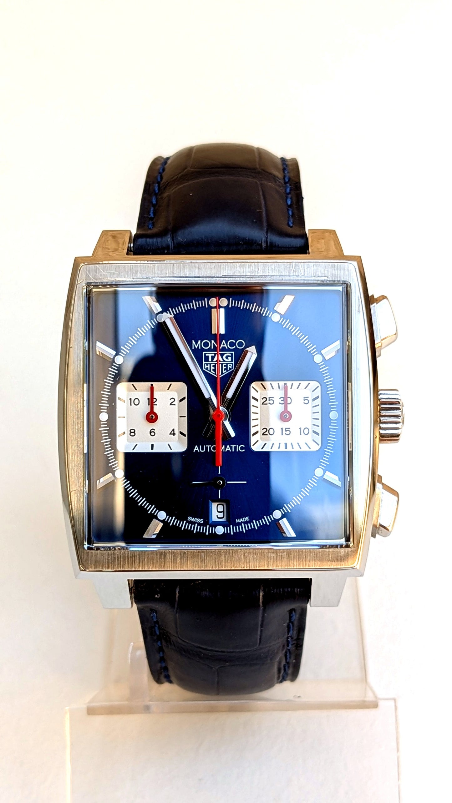 TAG Heuer Monaco de face sur support, cadran bleu, compteurs blancs et aiguille rouge, montre vintage homme